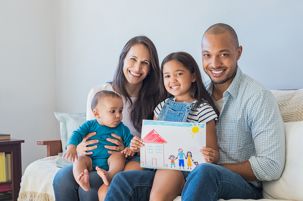 Daughter showing drawing of a happy family outside a new house.