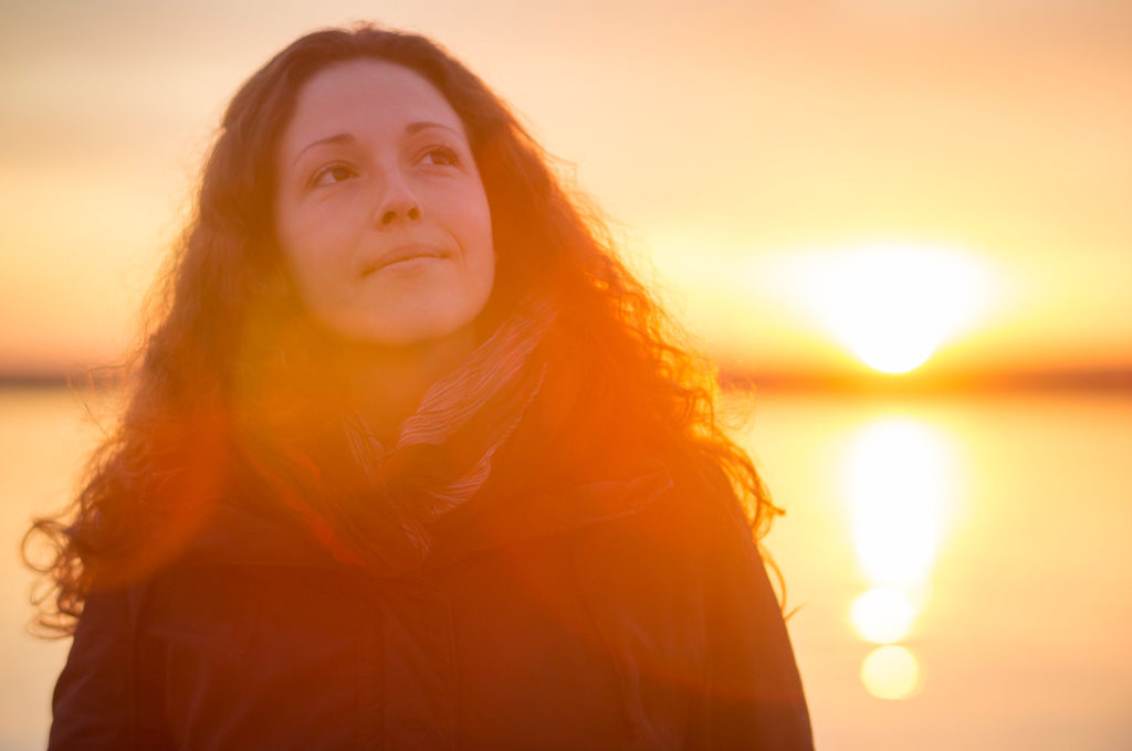 Beautiful young woman enjoying the beautiful sunset at the sea.